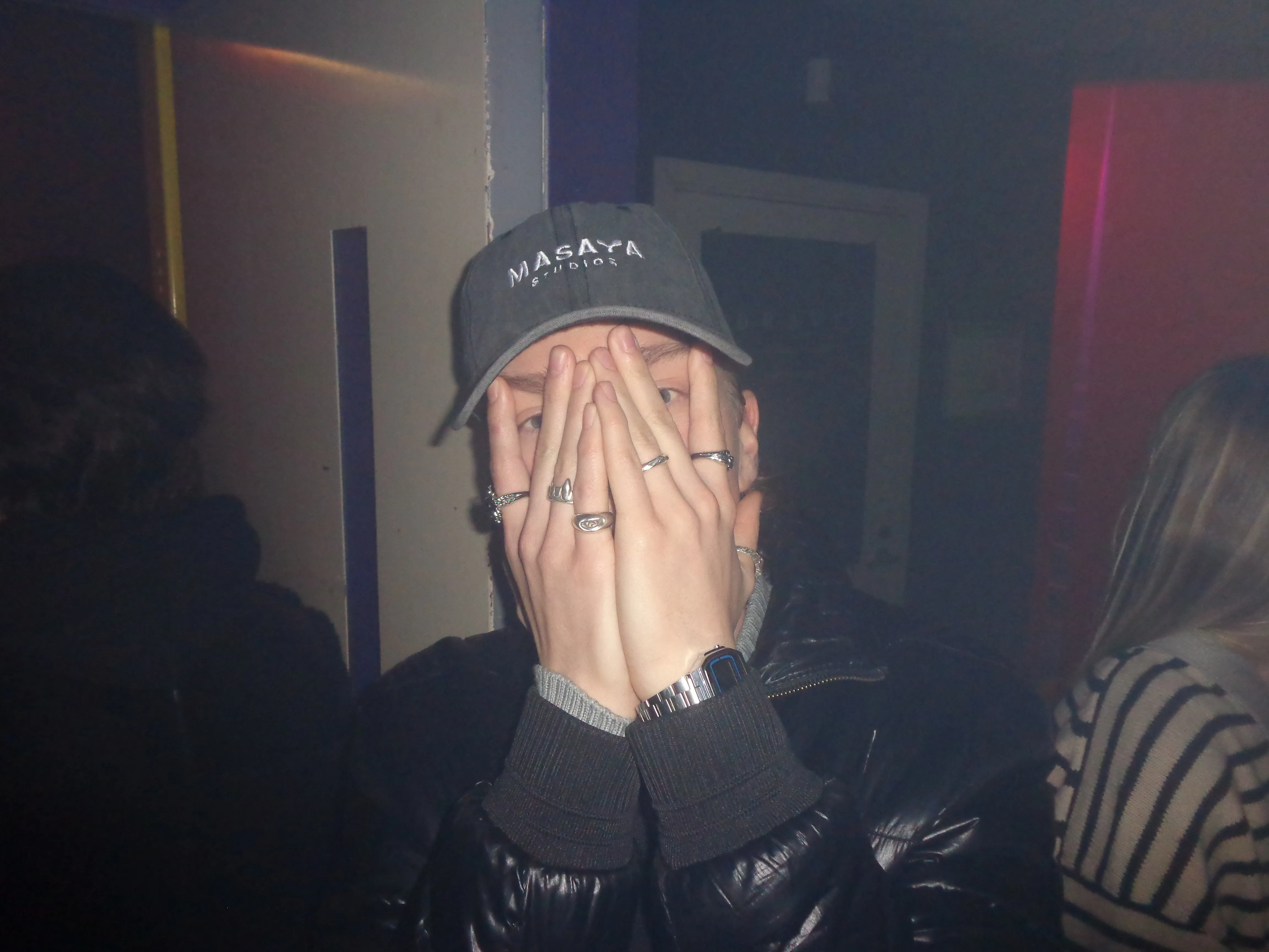 Someone in a Masaya Studios cap, photographed with a flash at night