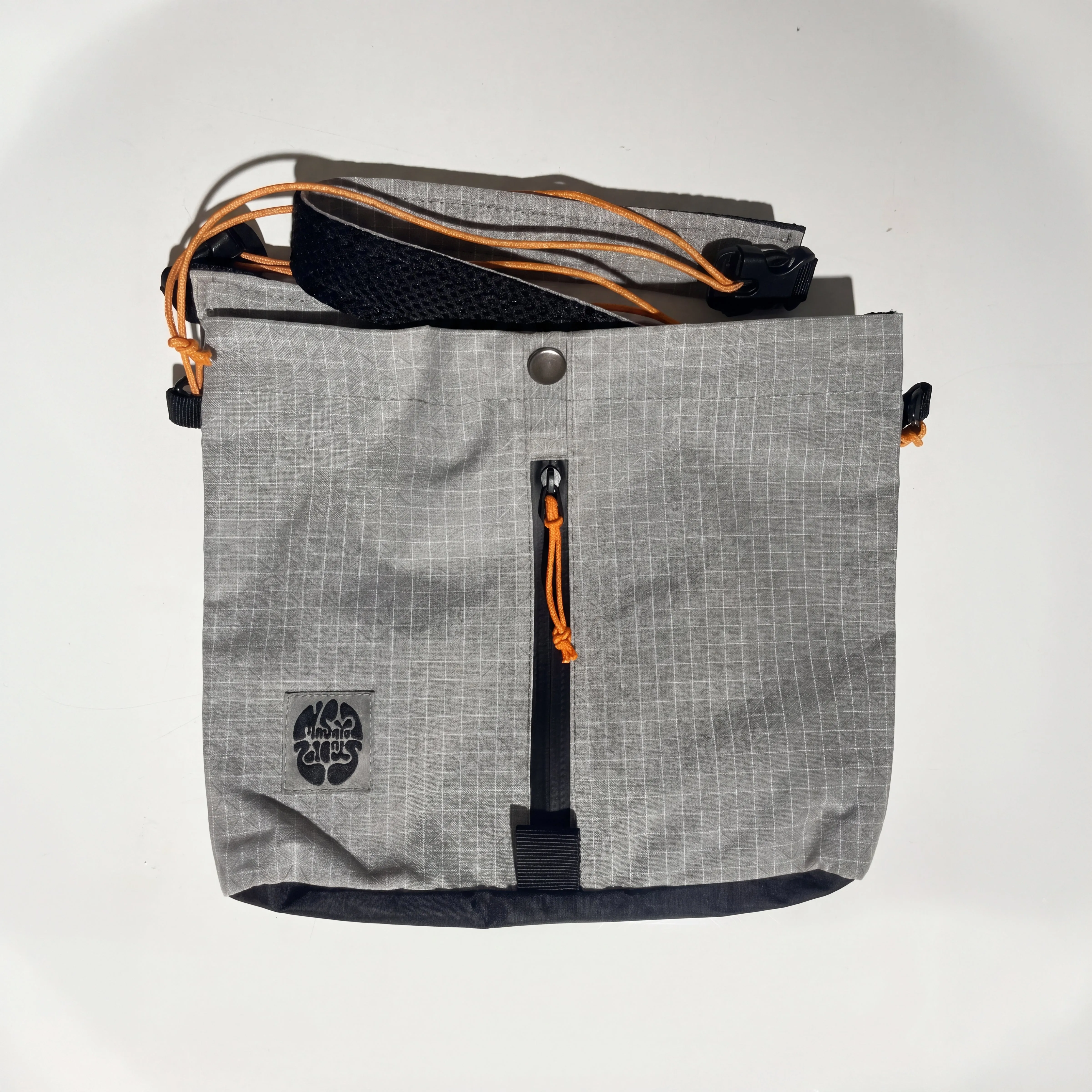 Masaya Slingbag i grått med orange snören, framficka och justerbar rem.